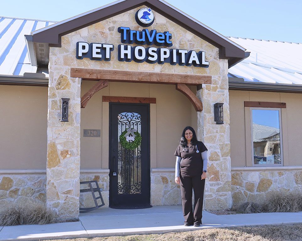 A woman standing in front of a pet hospital with a stone facade and a decorative door.
